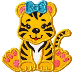 May include: A yellow and black striped tiger with a blue bow, pink paws, and a white belly. The tiger is sitting with its tail curled behind it.