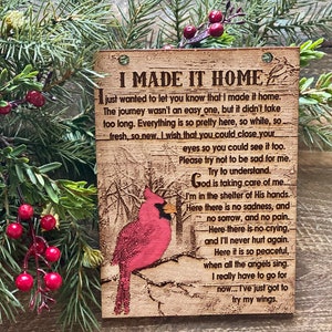 May include: A wooden sign with a red cardinal perched on a branch. The sign has the text "I Made It Home" and a poem about finding peace and comfort after a difficult journey.