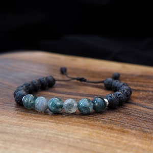 以下が含まれることがあります： 黒い溶岩ビーズと緑の瑪瑙ビーズで作られたブレスレット。ブレスレットは、サイズ調整のためのスライドノット付きの黒いコードが付いています。