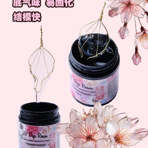 May include: Two bottles of UV Dip Resin, a clear resin for dipping wire petals. The bottles are labeled "UV Dip Resin" and "Dip Resin" and both have a 100ml capacity. The resin is shown being used to dip a wire flower petal in a clear, golden wire frame.