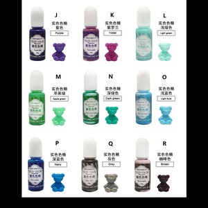 K&ouml;nnte beinhalten: Ein Set mit 10 kleinen Flaschen fl&uuml;ssigem Harzfarbpigment. Jede Flasche hat einen wei&szlig;en Verschluss und ein Etikett mit chinesischem und englischem Text. Der englische Text lautet "Solid Color Pigment". Die Flaschen sind in drei Reihen mit jeweils drei Flaschen angeordnet. Jede Flasche ist mit einer kleinen Harz-B&auml;renfigur in der gleichen Farbe wie die Fl&uuml;ssigkeit in der Flasche gepaart. Die Farben sind Lila, Violett, Hellgr&uuml;n, Apfelgr&uuml;n, Dunkelgr&uuml;n, Hellblau, Marineblau, Grau und Braun.
