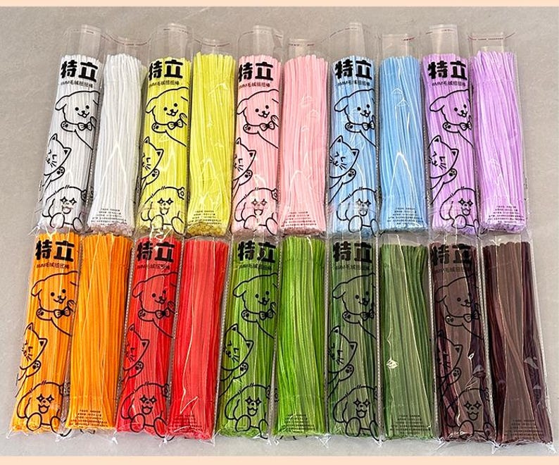 May include: A collection of 16 colorful bundles of thin, flexible, plastic straws. Each bundle is wrapped in clear plastic and features a cartoon dog and cat design with the text "特立" on the front.