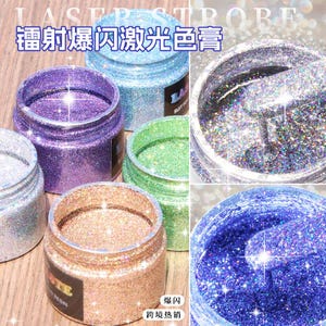 May include: A collection of small jars filled with glitter in various colors, including purple, blue, green, silver, and gold. The jars are open, revealing the sparkling contents. Text on the jars reads "LASER STROBE" and "SUIT FOR UV RESIN".