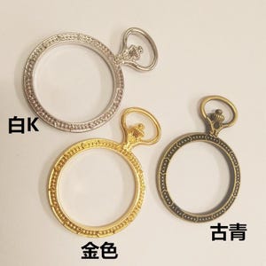 Pode incluir: Três bezéis de relógio de bolso de estilo antigo em prata, ouro e bronze. Cada bezel tem uma borda decorativa e um laço na parte superior.