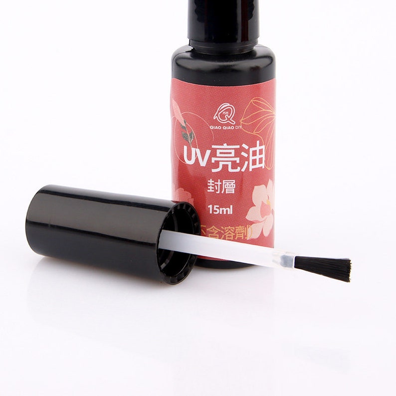 May include: A small black bottle with a white cap and brush applicator. The bottle label is red with white text that reads "UV 完油  封層 15ml  含香精".