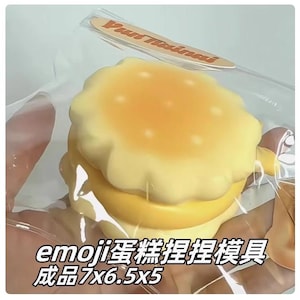 May include: A yellow and white squishy toy shaped like a hamburger. The toy is in a clear plastic bag with the text "Pun Training" on it. The text "emoji  squishy holder holder 7x6.5x5" is on the bottom of the image.