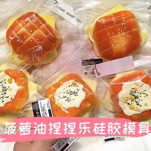 May include: A set of four silicone molds for making pineapple bun shaped pastries. The molds are in clear plastic packaging and feature a variety of pineapple bun designs. The packaging includes the text "菠萝油捏捏乐硅胶模具" in Chinese.