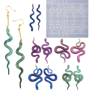 Puede incluir: Un conjunto de pendientes de resina con forma de serpiente iridiscente y un molde de silicona para hacer más pendientes. El molde tiene 12 formas de serpiente de diferentes tamaños. Los pendientes son en tonos de verde, azul y morado.