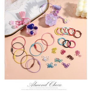 May include: Assortment of colourful keychains and metal rings. The keychains feature a paw print design, a tassel, and a small charm. The metal rings are in various colours and sizes.