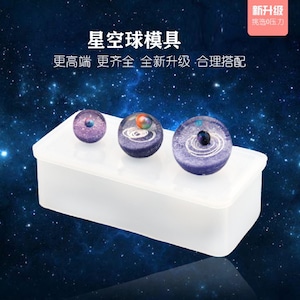 May include: Three clear resin galaxy sphere molds in a white rectangular silicone mold. The spheres are different sizes and feature a swirling galaxy design with a small black sphere in the center.