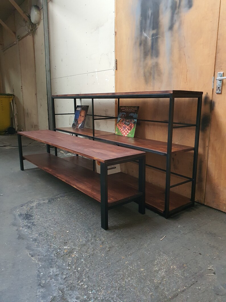 May include: Two wooden shelves with a dark finish and black metal frames. The shelves are rectangular and have multiple levels for storage. One is a low, long bench, and the other is a taller, wider unit. Books are displayed on the shelves.