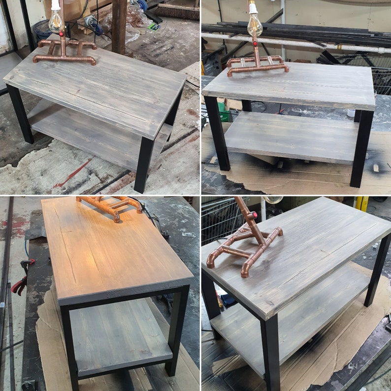 May include: A gray-stained wooden coffee table with a lower shelf and black metal legs. A copper pipe lamp with a lightbulb sits on top. The table is approximately 40 inches long, 20 inches wide, and 18 inches high.