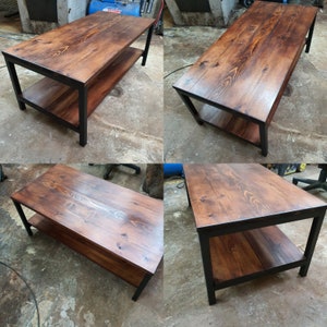 May include: A rectangular coffee table with a dark stained wood top and lower shelf. The frame is black metal. The table is approximately 48 inches long, 24 inches wide, and 18 inches high.
