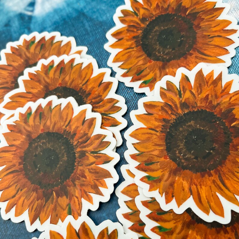 Peut inclure: Plusieurs autocollants repr&eacute;sentant des tournesols. Chaque autocollant pr&eacute;sente une peinture &agrave; l'aquarelle d&eacute;taill&eacute;e d'un tournesol avec des p&eacute;tales orange et un centre brun fonc&eacute;. Les autocollants ont une bordure blanche.