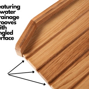 May include: Close-up of a wooden cutting board with six water drainage grooves and an angled surface. The board is made of light brown wood and features a natural wood grain pattern. The text "Featuring 6 water drainage grooves with angled surface" is visible.