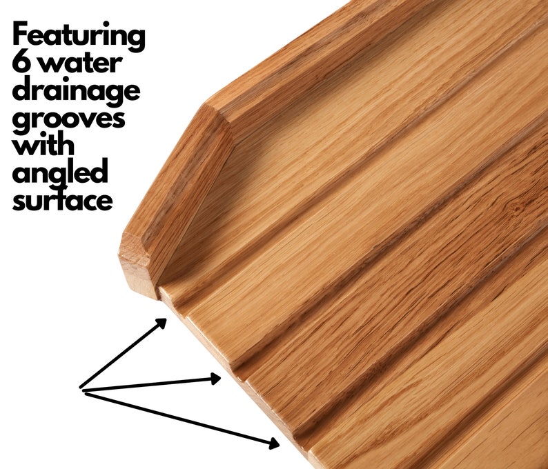 May include: Close-up of a wooden cutting board with six water drainage grooves and an angled surface. The board is made of light brown wood and features a natural wood grain pattern. The text "Featuring 6 water drainage grooves with angled surface" is visible.