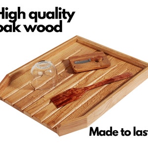 May include: A wooden dish drying rack made of oak wood. The rack has a rectangular shape with slatted design. A glass, a small wooden cutting board with a knife, and a wooden spatula are on the rack. The text "High quality oak wood" and "Made to last" are visible.