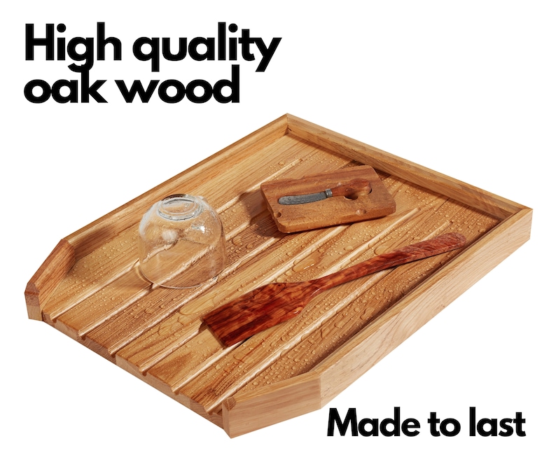 May include: A wooden dish drying rack made of oak wood. The rack has a rectangular shape with slatted design. A glass, a small wooden cutting board with a knife, and a wooden spatula are on the rack. The text "High quality oak wood" and "Made to last" are visible.