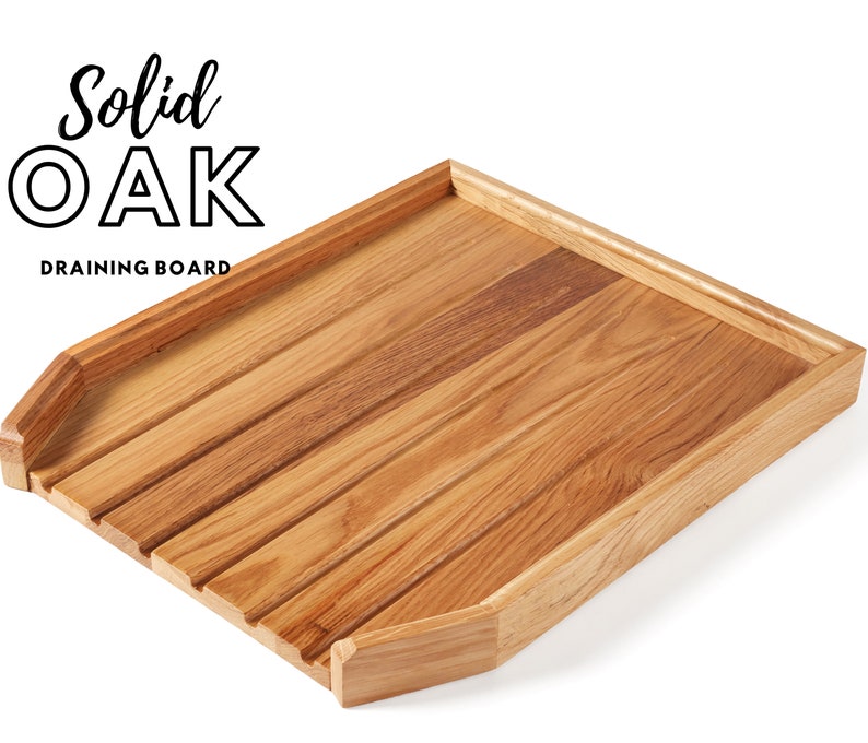 May include: A solid oak draining board with a natural wood grain finish. The board features a slatted design for efficient water drainage and a raised edge to contain spills. The text "Solid Oak Draining Board" is displayed in black.