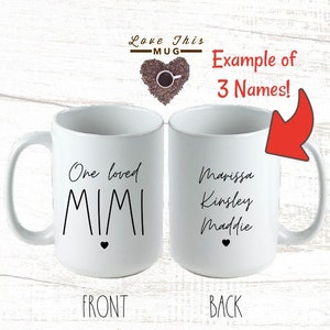 May include: White ceramic mug with a black heart and the text "One loved MIMI" on the front. The back of the mug has the text "Marissa Kinsley Maddie" on it.