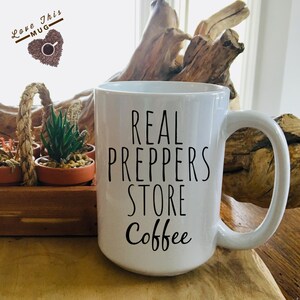 May include: White ceramic coffee mug with black text that reads "REAL PREPPERS STORE Coffee".