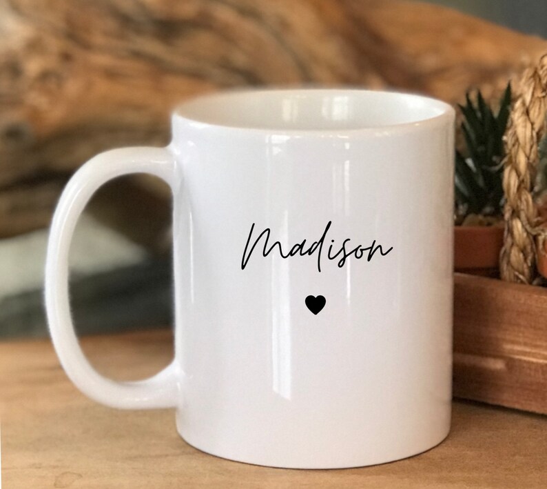 May include: White ceramic mug with a black handwritten name "Madison" and a small black heart.