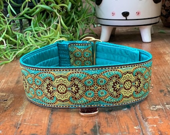 Könnte beinhalten: Ein türkisfarbenes Hundehalsband mit einem verzierten, gemusterten Design in Braun-, Gelb- und Türkistönen. Das Halsband hat goldfarbene Beschläge und einen braunen Lederakzent. Das Halsband ist etwa 5 cm breit.