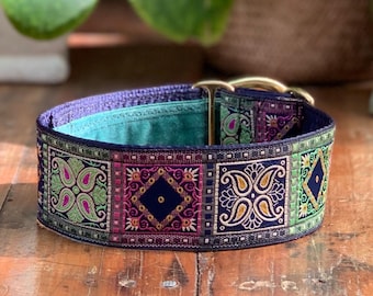 Könnte beinhalten: Ein dekoratives Hundehalsband mit marineblauem Grund und bunten Stickmustern. Das Halsband hat eine goldfarbene Metallschnalle und eine türkisfarbene Innenseite. Die Stickereien zeigen Paisley- und Rautenformen in Grün, Pink und Lila.