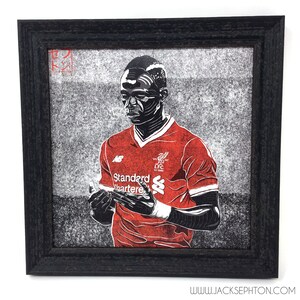 May include: A black and white illustration of a soccer player wearing a red jersey with the text "Standard Chartered" and the Liverpool Football Club logo. The player is in a thoughtful pose with his hands clasped together.