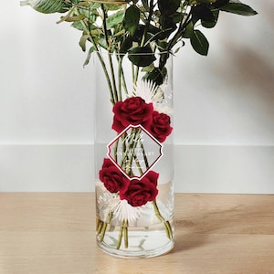 May include: A clear glass vase with a diamond-shaped design that says "Happy Anniversary". The vase is filled with red roses and white flowers.