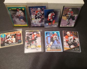 May include: A collection of nine hockey trading cards featuring Eric Lindros, a professional hockey player. The cards are in various conditions, some are new and some are used. The cards are from different years and feature different designs.