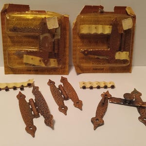 Puede incluir: Dos paquetes de bisagras de estilo antiguo en acabado cobre. Las bisagras están empaquetadas en plástico transparente con fondo amarillo y blanco. Los paquetes tienen el texto "Colonial Colonial" impreso en ellos. Las bisagras se muestran desmontadas y listas para usar.