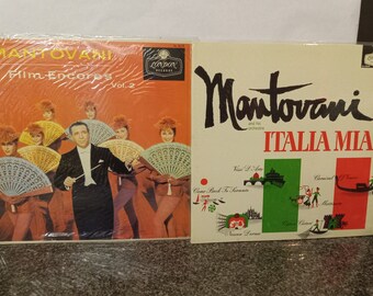 May include: Two vintage vinyl record albums by Mantovani. The first album is titled "Film Encores Vol. 2" and features a colorful image of Mantovani conducting an orchestra with women holding fans. The second album is titled "Italia Mia" and features a map of Italy with various landmarks and scenes.