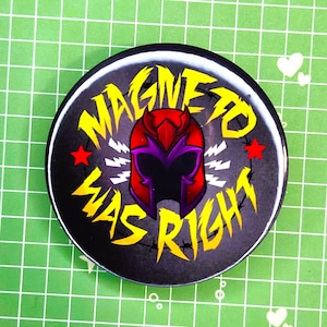 May include: A round button with a black background featuring the text "MAGNETO WAS RIGHT" in yellow, with a red and purple helmet graphic. Two red stars and white lightning bolts are also present.