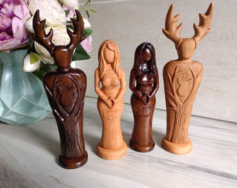 Puede incluir: Cuatro esculturas de madera de figuras con cornamentas y formas femeninas. Las esculturas están talladas en madera en varios tonos de marrón y beige. Las figuras tienen tallas detalladas de árboles y otros elementos naturales.