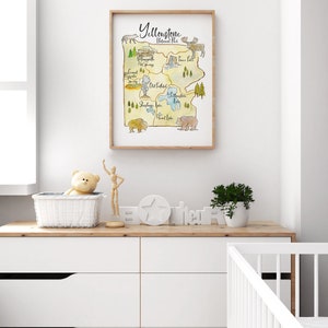 May include: A watercolor illustration of Yellowstone National Park, featuring landmarks like Old Faithful, Yellowstone Lake, and Tower Fall. The illustration is surrounded by a brown frame and includes images of a bison, a bear, and an elk.