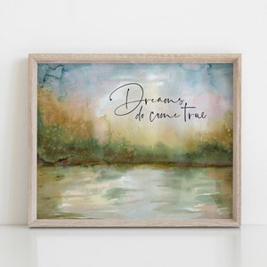 May include: A framed watercolor painting of a lake with trees in the background. The text "Dreams do come true" is written in black cursive script on the painting.
