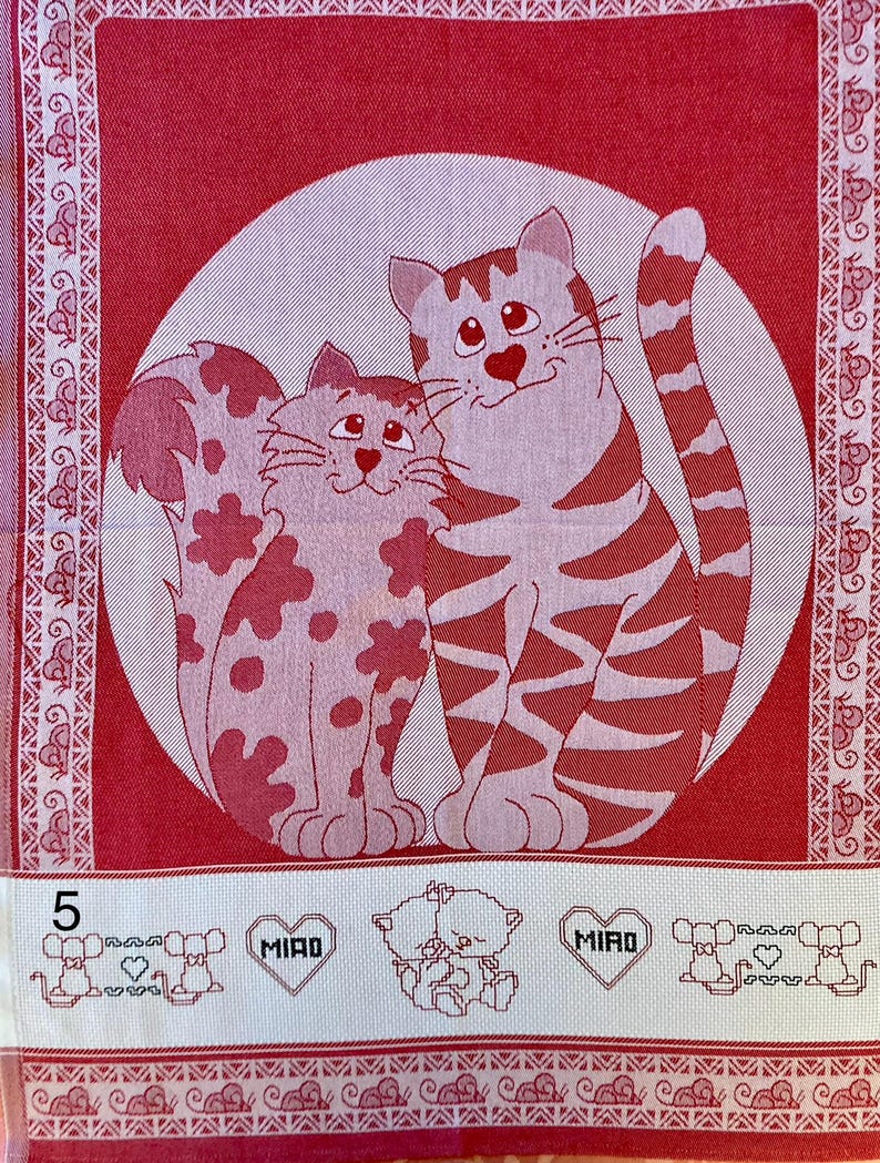 Peut inclure: Serviette de cuisine rouge avec un cercle blanc au centre repr&eacute;sentant deux chats. Les chats sont un chat tigr&eacute; et un chat tachet&eacute;. La serviette a une bordure blanche avec un motif r&eacute;p&eacute;titif de souris. Le bas de la serviette a une section blanche avec un motif r&eacute;p&eacute;titif de souris et le mot "MIRO" en forme de c&oelig;ur.
