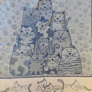 Peut inclure: Une serviette de cuisine bleue et blanche avec un motif de chats. Les chats sont tous de couleurs diff&eacute;rentes et ont des expressions diff&eacute;rentes. La serviette porte le num&eacute;ro 3. Le texte "Tessitura Artistica Chierese" est imprim&eacute; en bas de la serviette.