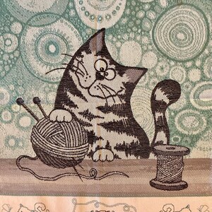 Peut inclure: Un chat brun et blanc &agrave; l'air joueur est assis avec une pelote de laine et des aiguilles &agrave; tricoter. Le chat est sur un fond vert et blanc avec un motif circulaire. L'image comprend &eacute;galement une bobine de fil et trois chats plus petits dans la bordure inf&eacute;rieure.