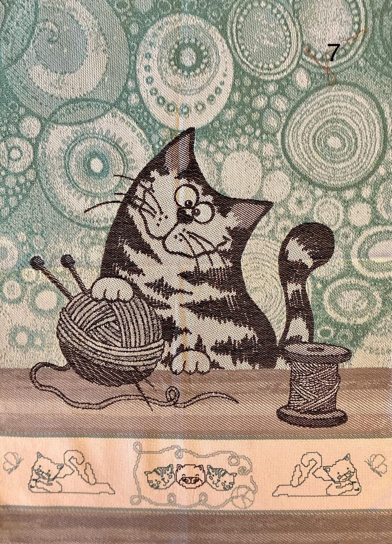 Peut inclure: Un chat brun et blanc &agrave; l'air joueur est assis avec une pelote de laine et des aiguilles &agrave; tricoter. Le chat est sur un fond vert et blanc avec un motif circulaire. L'image comprend &eacute;galement une bobine de fil et trois chats plus petits dans la bordure inf&eacute;rieure.