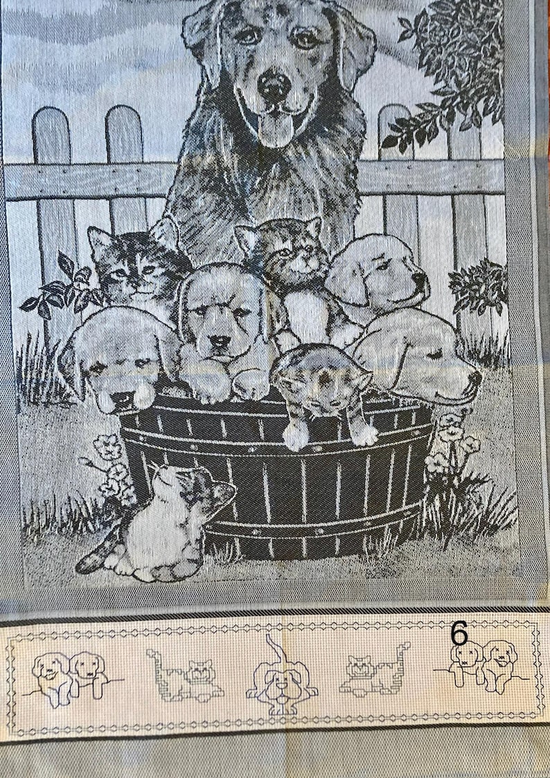 Peut inclure: Une tapisserie en noir et blanc repr&eacute;sentant un grand chien avec un groupe de chiens et de chats plus petits dans un tonneau. La tapisserie a un fond gris avec une cl&ocirc;ture blanche et une v&eacute;g&eacute;tation verte.