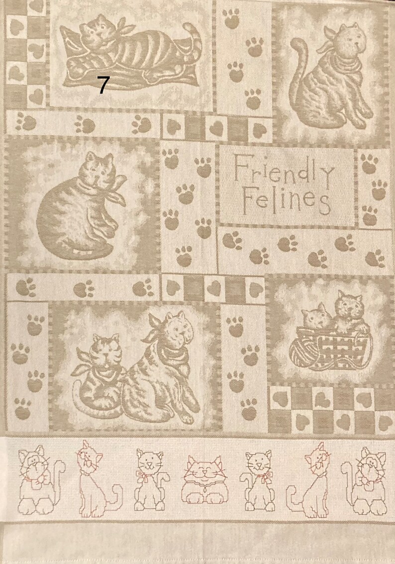 May include: A beige fabric with a patchwork design featuring cats and paw prints. The text "Friendly Felines" is printed in the center of the fabric.