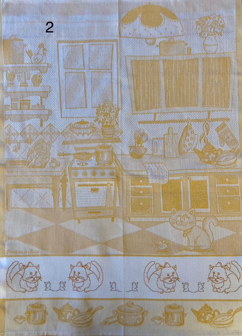 Peut inclure: Une serviette de cuisine jaune sur fond blanc repr&eacute;sentant une sc&egrave;ne de cuisine avec une cuisini&egrave;re, des armoires et une fen&ecirc;tre. La serviette est bord&eacute;e de chats et de souris. Le chiffre "2" se trouve dans le coin sup&eacute;rieur gauche de la serviette. Le texte "Prodotto in Italia" se trouve dans le coin inf&eacute;rieur gauche de la serviette.