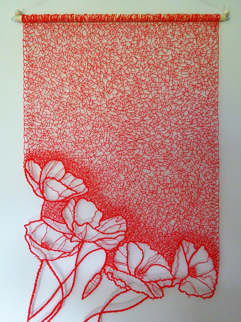 Puede incluir: Un tapiz de pared de arte de hilo rojo con un dise&ntilde;o de flores. Las flores est&aacute;n delineadas con hilo rojo y est&aacute;n parcialmente oscurecidas por el fondo de hilo rojo.