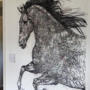 May include: A black and white wire sculpture of a horse in mid-air, with its mane flowing in the wind. The sculpture is made of many small, intertwined wires, creating a detailed and intricate design.