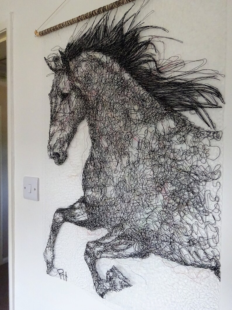 May include: A black and white wire sculpture of a horse in mid-air, with its mane flowing in the wind. The sculpture is made of many small, intertwined wires, creating a detailed and intricate design.
