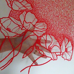 Puede incluir: Dise&ntilde;o floral rojo impreso en 3D con una mano sosteniendo la parte inferior del dise&ntilde;o. El dise&ntilde;o est&aacute; hecho de l&iacute;neas finas e intrincadas que crean un efecto delicado y aireado.