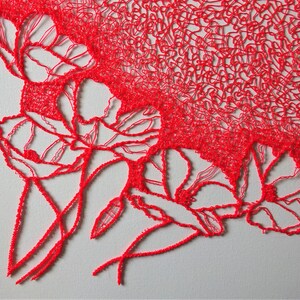 Puede incluir: Primer plano de un dise&ntilde;o floral rojo, intrincado, creado con una pluma 3D. El dise&ntilde;o presenta l&iacute;neas y curvas delicadas, que se asemejan a un ramo de flores.
