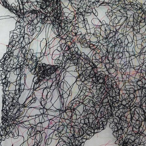 May include: A black and white abstract art piece made of thread. The thread is woven together to create a design that resembles a face.
